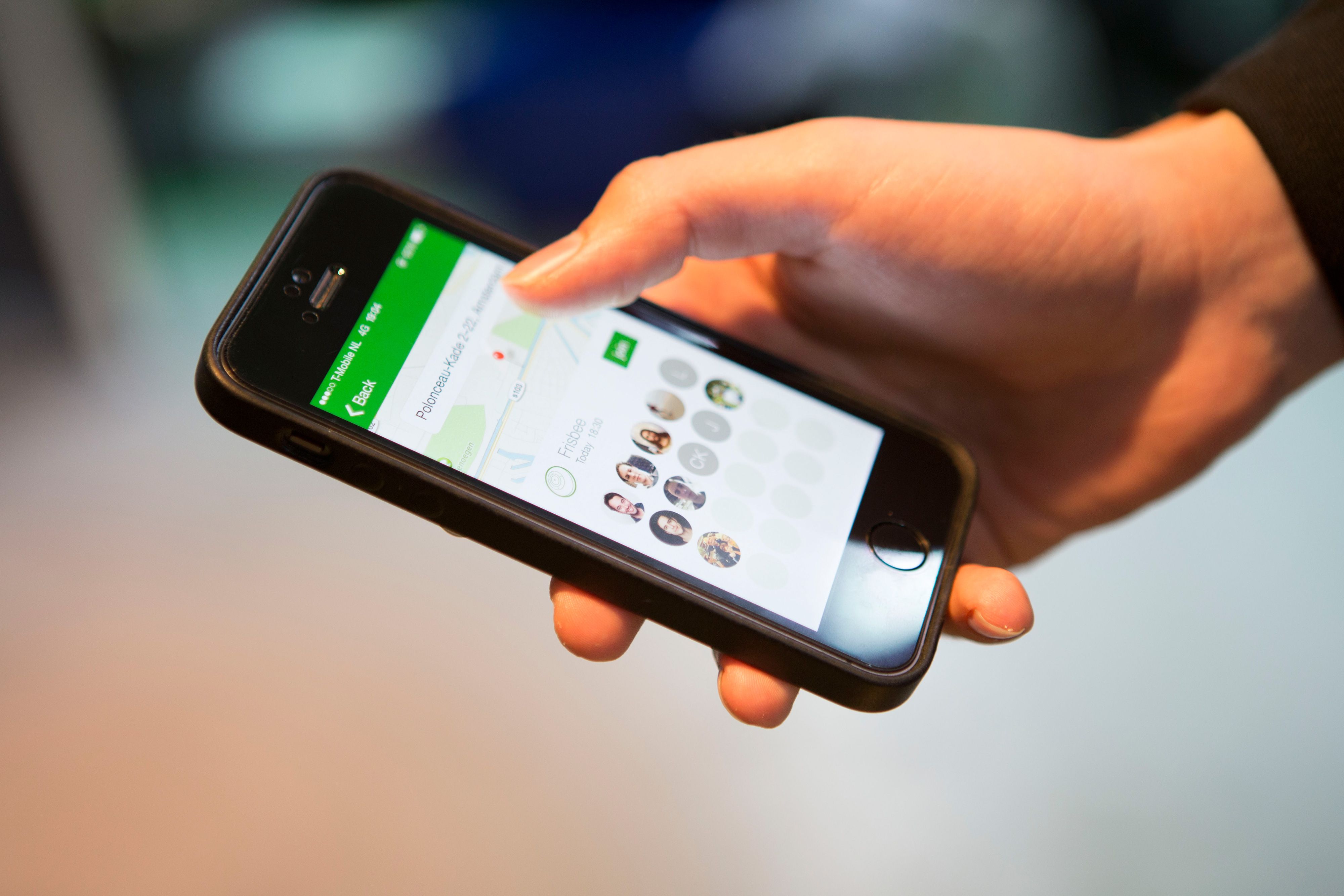 A hand holding a phone with the Let's Play app showing nearby players on a map